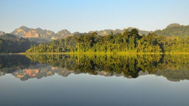 Die bewaldeten Hügel spiegeln sich in der ruhigen Wasseroberfläche.