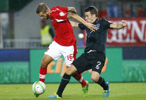 Zwei Fußballspieler kämpfen im Regen um den Ball.