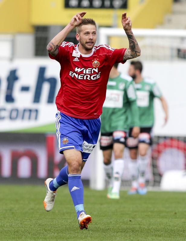 Ein Fußballspieler in rotem Trikot jubelt auf dem Spielfeld.