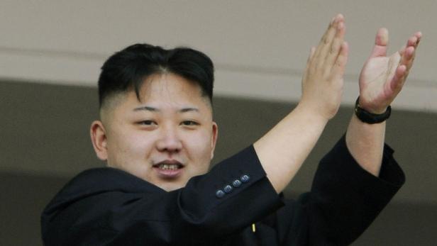 Kim Jong-un winkt mit beiden Händen.