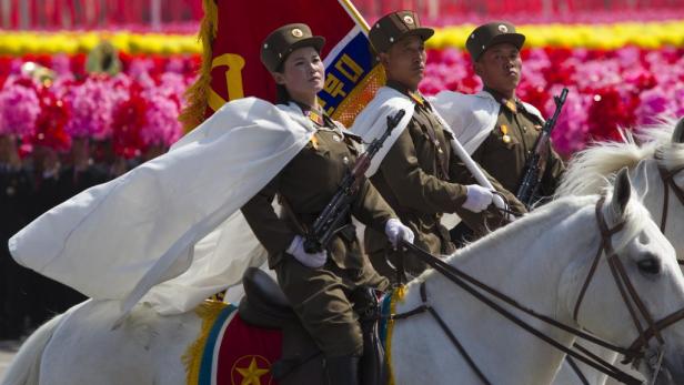 Nordkoreanische Soldatinnen und Soldaten reiten auf weißen Pferden bei einer Parade.
