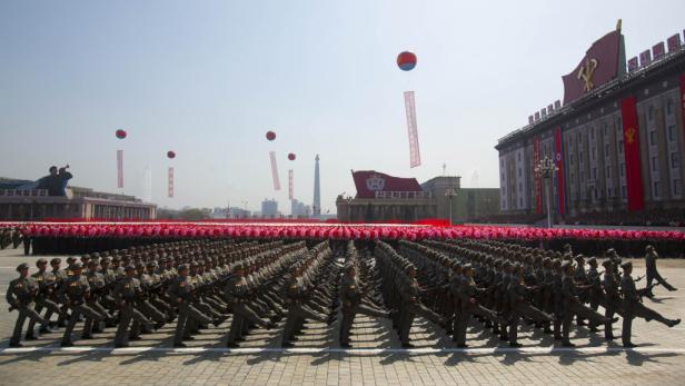Eine Militärparade in Nordkorea mit Soldaten und roten Bannern.