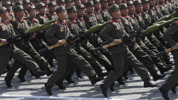 Nordkoreanische Soldaten marschieren mit Gewehren und Granatwerfern.