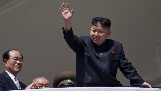 Kim Jong-un winkt von einem Balkon, umgeben von anderen Würdenträgern.