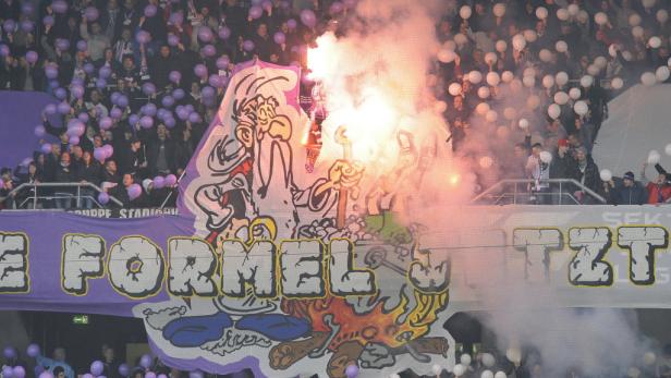 Fans zünden Fackeln hinter einem großen Banner mit einer Comicfigur.