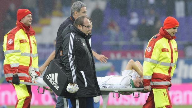 Sanitäter tragen einen verletzten Fußballspieler auf einer Trage vom Spielfeld.