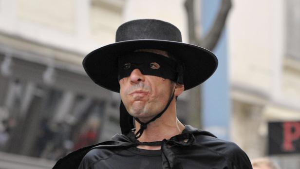 Ein Mann, verkleidet als Zorro, mit schwarzer Maske und Hut.