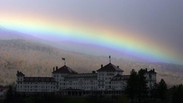 Ein Regenbogen erstreckt sich über ein großes, weißes Hotelgebäude.