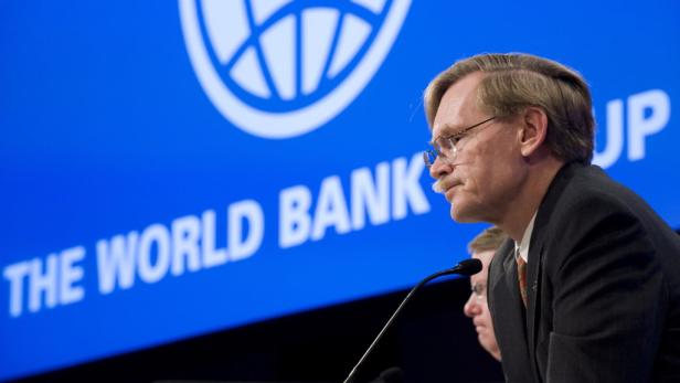 Ein Mann mit Brille spricht vor einem Mikrofon mit dem Logo der Weltbank im Hintergrund.