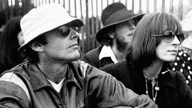 Eine Gruppe von Menschen mit Hüten und Sonnenbrillen in Schwarzweiß.