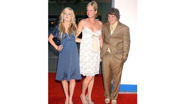 Eine junge Frau, eine Frau mittleren Alters und ein junger Mann posieren auf einem roten Teppich.