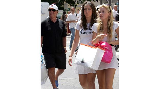 Zwei junge Frauen mit Einkaufstüten und ein älterer Mann gehen die Straße entlang.