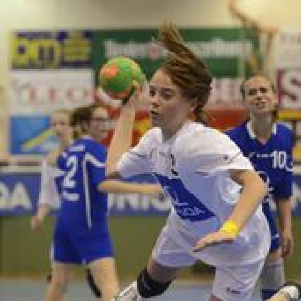 Eine junge Frau wirft einen Handball während eines Spiels.