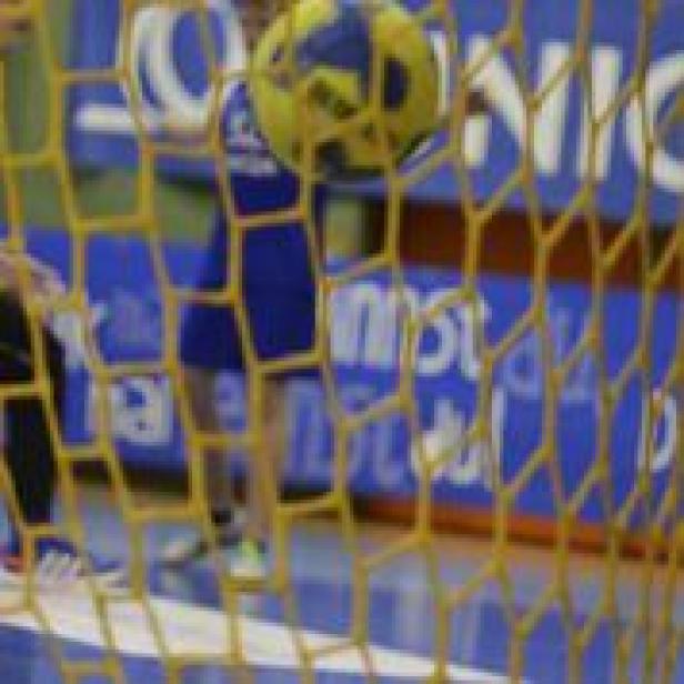 Ein gelb-blauer Ball fliegt durch ein gelbes Netz.