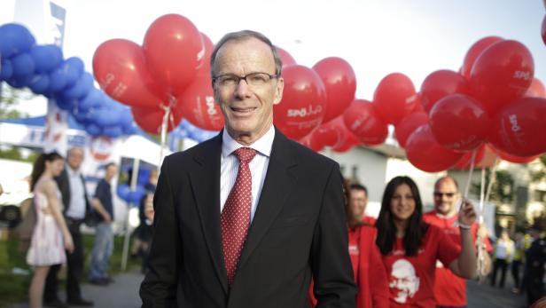Ein Mann in Anzug steht vor roten und blauen Luftballons einer SPD-Veranstaltung.