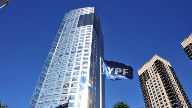 Das YPF-Hauptquartier und argentinische Flaggen vor blauem Himmel.