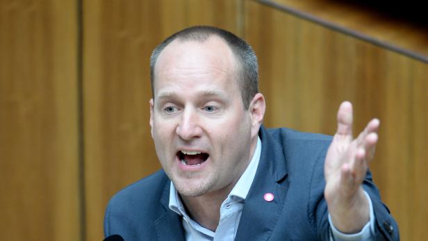 Ein Mann in einem Anzug gestikuliert und spricht.