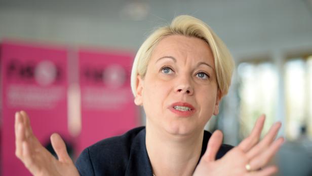 Eine Frau mit blonden Haaren gestikuliert mit ihren Händen.