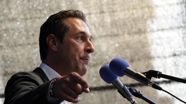 Ein Mann spricht vor zwei Mikrofonen und gestikuliert mit der Hand.