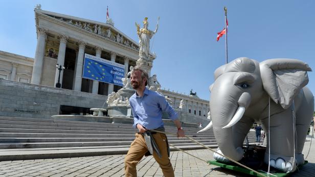 Ein Mann zieht einen aufblasbaren Elefanten vor dem österreichischen Parlament.