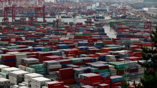 Ein Containerhafen mit unzähligen bunten Containern und Kränen im Hintergrund.