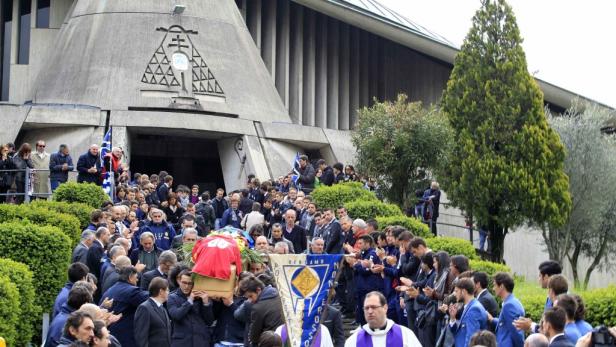 Menschen nehmen an einer Beerdigung vor einer Kirche teil.