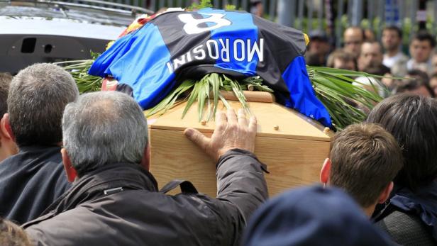 Ein Sarg wird von Trauernden getragen, geschmückt mit einem Trikot mit der Aufschrift „Morosini“.