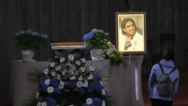 Eine Frau steht vor einem Altar mit Blumen und einem Porträt von Andrea Fortunato.