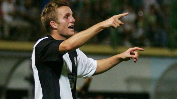 Ein Fußballspieler in einem schwarz-weißen Trikot gestikuliert auf dem Spielfeld.