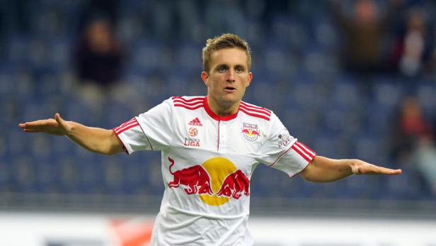 Ein Fußballspieler mit ausgebreiteten Armen im Trikot von Red Bull Salzburg.