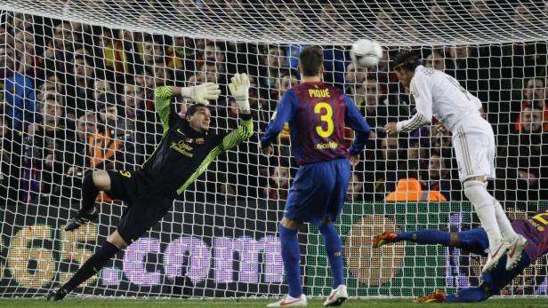 Ein Fußballspieler köpft den Ball, während der Torwart versucht, ihn abzuwehren.