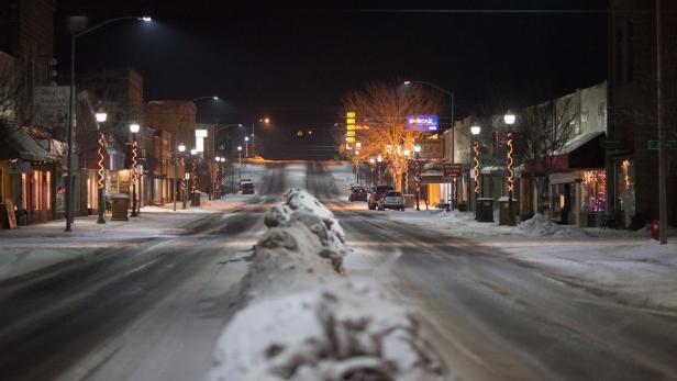 Eine verschneite Hauptstraße in einer Kleinstadt bei Nacht.