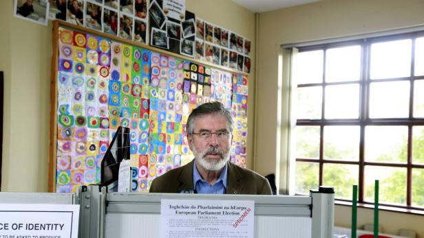 Gerry Adams hinter einem Tisch mit Wahlhinweisen für die Europawahl.
