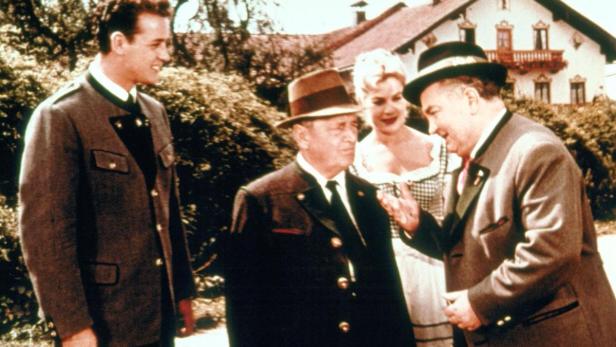 Vier Personen in Tracht stehen vor einem Haus im bayerischen Stil.