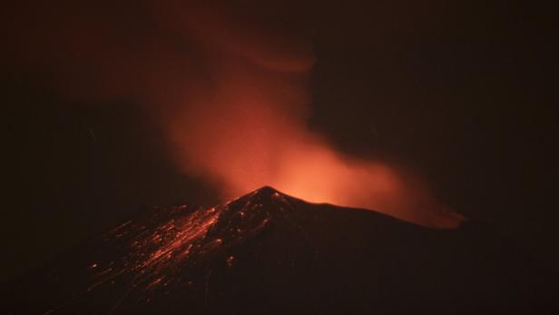 Ein Vulkan bricht nachts aus und speit Lava und Asche.