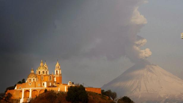 Die Kirche von Cholula vor dem rauchenden Vulkan Popocatépetl.