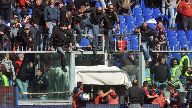 Fußballfans klettern über eine Absperrung im Stadion.