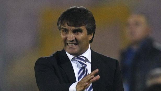 Ein Mann in Anzug und Krawatte gestikuliert mit der Hand.