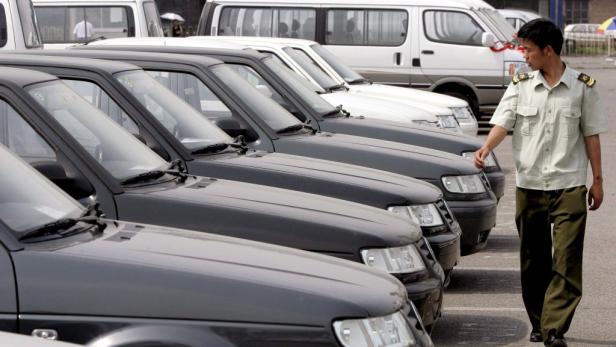 Ein Mann in Uniform geht an einer Reihe geparkter Autos vorbei.