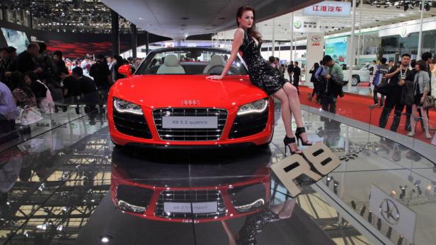 Eine Frau posiert auf einem roten Audi R8 5.2 quattro auf einer Automesse.