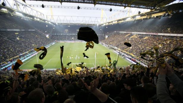 Volles Fußballstadion mit Fans, die Fahnen schwenken.