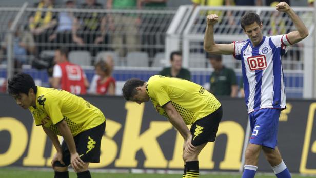 Ein Fußballspieler von Hertha BSC jubelt, während zwei Spieler von Borussia Dortmund enttäuscht sind.