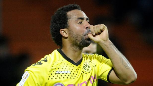 Ein Fußballspieler im gelben Trikot von Borussia Dortmund jubelt mit dem Finger im Mund.