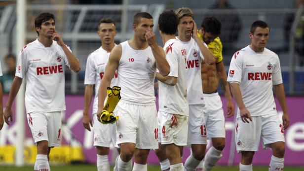 Eine Gruppe Fußballspieler des 1. FC Köln in ihren weißen Trikots auf dem Spielfeld.