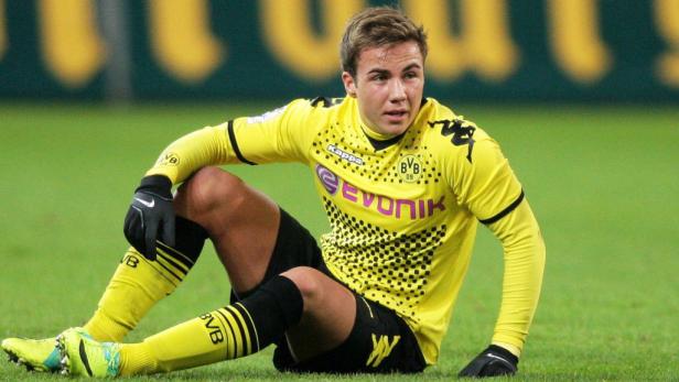Mario Götze im gelben Trikot von Borussia Dortmund sitzt auf dem Rasen.