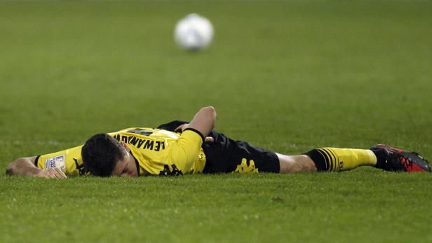 Ein Fußballspieler liegt erschöpft auf dem Rasen.