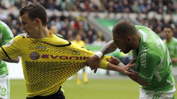 Ein Fußballspieler im grünen Trikot zerrt an dem gelben Trikot eines Gegenspielers.