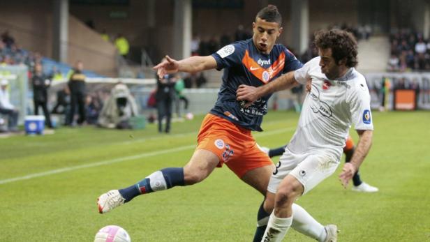Zwei Fußballspieler kämpfen um den Ball auf dem Spielfeld.