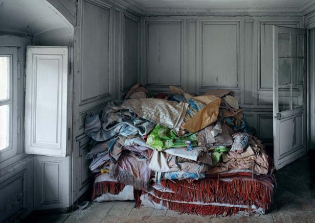 Ein großer Haufen Textilien liegt in einem Zimmer mit geöffneter Tür und Fenster.