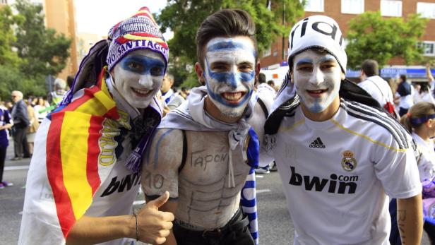 Drei Real Madrid-Fans mit Gesichtsbemalung posieren für ein Foto.